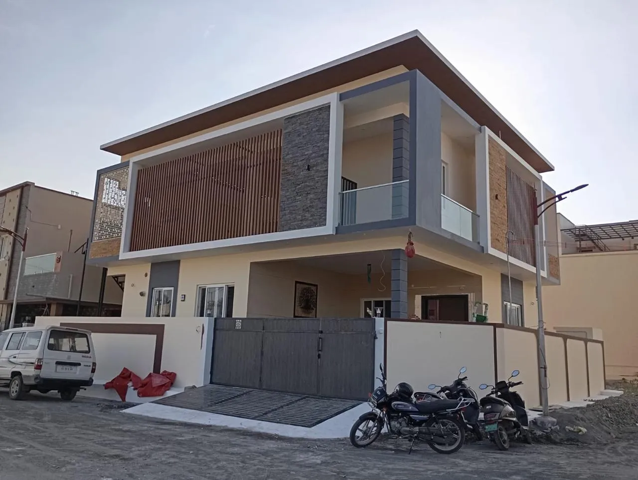 Modern corner-plot house with ivory walls, grey columns and timber louvre panels